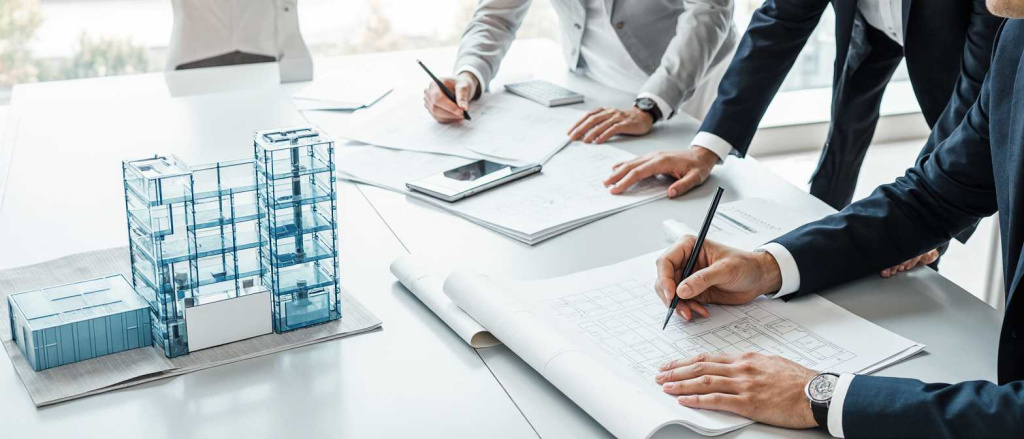 professional_architect_team_reviewing_architectural_blueprints_and_3d_building_model_on_large_desk__ulsc7tlvws6d43whm9n1_2.jpg